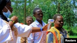 FILE - A Congolese health worker checks the temperature of a man before the launch of vaccination campaign against the deadly Ebola virus near Mangina village, near the town of Beni in North Kivu province of the Democratic Republic of Congo, Aug. 8, 2018.