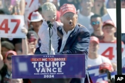 Calon presiden dari Partai Republik, mantan Presiden Donald Trump menggendong cucunya, Luke Trump, saat berkampanye di Bandara Internasional Wilmington di Wilmington, AS, 21 September 2024. (Foto: AP)