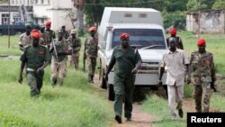 South Sudanese soldiers guard their colleagues, suspected of rape and murder, as they ride in a van before appearing in military in South Sudan's capital Juba, May 30, 2017.