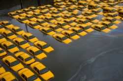 FILE - In this Tuesday, Oct. 30, 2012 file photo, a parking lot full of yellow cabs is flooded as a result of Superstorm Sandy in Hoboken, NJ. (AP Photo/Charles Sykes)