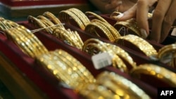 Picture taken on September 1, 2010 shows Myanmar vendors arranging a display of gold jewellery at a jewellery shop at Chinatown in downtown Yangon. Housewives huddle over jewellery counters in Yangon's bustling Chinatown -- but they do not have fashion o