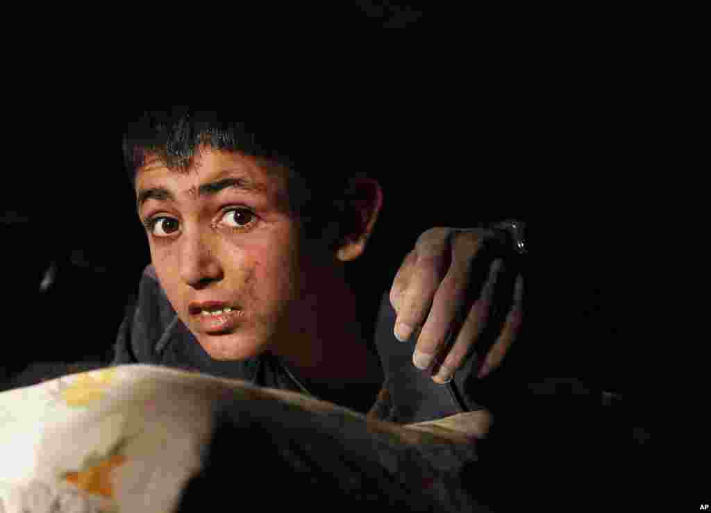 Yunus, a 13-year-old earthquake survivor with a hand of a victim on his shoulder, waits to be rescued from under a collapsed building by rescue workers in Ercis, near the eastern Turkish city of Van, early October 24, 2011. (Reuters)