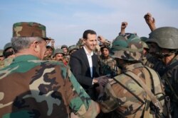 FILE - Syrian soldiers cheer President Bashar al-Assad during his visit to al-Habit on the southern edges of the Idlib province, in this handout picture released by the official Facebook page for the Syrian Presidency, Oct. 22, 2019.