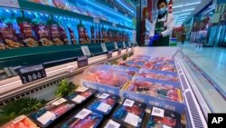 A worker wearing a mask and gloves stand near beef products from New Zealand packaged with a QR-code linked to its coronavirus test results displayed at a supermarket in Beijing, Tuesday, Nov. 24, 2020. China has stirred controversy with claims it…