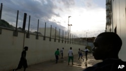 FILE - Migrants play soccer inside a temporary camp, after a fiery shipwreck of a fishing boat packed with 500 migrants from Eritrea, in Lampedusa, Italy, Oct. 6, 2013.