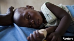 FILE - A young girl with malaria rests in the inpatient ward of the Malualkon Primary Health Care Center in Malualkon, in the South Sudanese state of Northern Bahr el-Ghazal, June 1, 2012. 