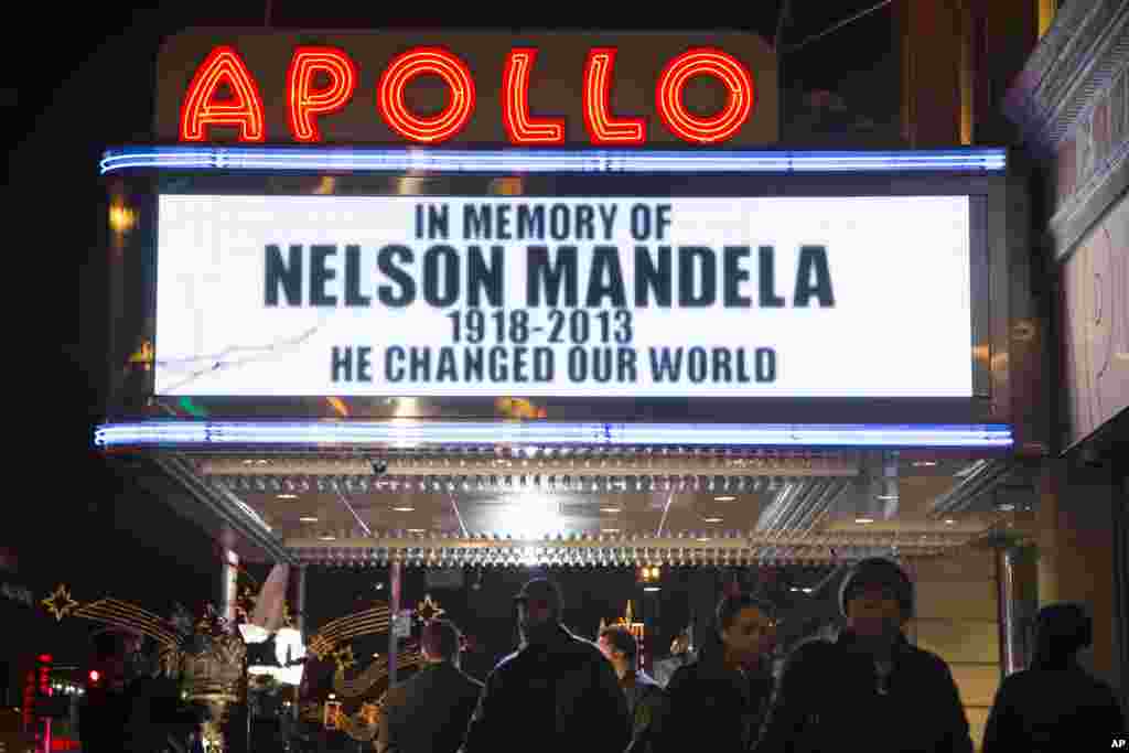 Pedestrians pass beneath the Apollo Theater marquee commemorating the life of South African leader Nelson Mandela in the Harlem neighborhood of New York, Dec. 5, 2013.