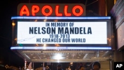 Pedestrians pass beneath the Apollo Theater marquee commemorating the life of South African leader Nelson Mandela in the Harlem neighborhood of New York, Dec. 5, 2013.