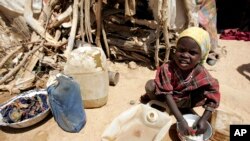 FILE - A young girl washes clothes outside her shack at the Iridimi refugee camp near Iriba in eastern Chad, Sept. 25, 2004. 