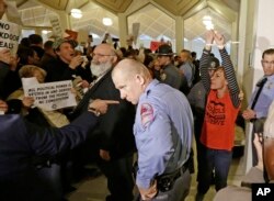 A protester, right, is handcuffed and removed from the House gallery as demonstrators interrupted a special session at the North Carolina Legislature in Raleigh, N.C., Thursday, Dec. 15, 2016.