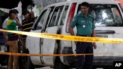 Members of Bangladeshi police and detective branch stand by the site where Italian citizen Cesare Tavella was gunned down by unidentified assailants in Dhaka, Sept. 29, 2015.