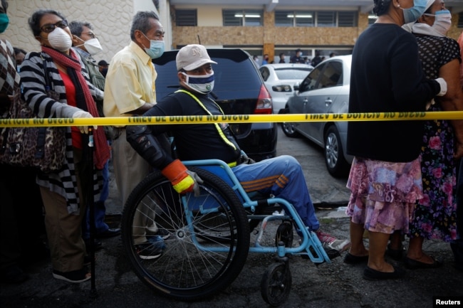 Un hombre hace fila frente al Centro Nacional de Cuidados y Administración de Subsidios (CENADE) para averiguar si es elegible para ayuda económica en San Salvador.