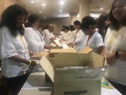 Volunteers of all ages pack hygiene kits for local homeless at long, narrow assembly lines. (Photo: Leslie Bonilla/VOA)
