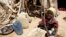 FILE - A young girl washes clothes outside her shack at the Iridimi refugee camp near Iriba in eastern Chad, Sept. 25, 2004. 