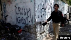 Policeman walks past graffiti directed at local media house Geo TV, Karachi, May 20, 2014.