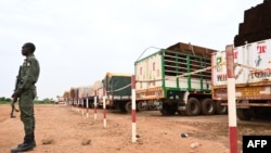 A Niger's police officer stands guard next to some of the 300 trucks mainly loaded with food that arrived from Burkina Faso in Niamey on August 21, 2023.