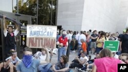 A group of demonstrators sit outside the entrance to the National Air and Space Museum in Washington after police pepper-sprayed a group of protestors trying to get into the museum Saturday, Oct. 8, 2011.