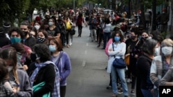 Chilenos en Santiago hacen fila el domingo 25 de octubre de 2020, para decidir con su voto si el país debe reemplazar su constitución de cuatro décadas.