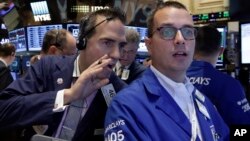 Trader Gregory Rowe, left, talks to specialist Neil Gallagher as they work on the floor of the New York Stock Exchange, Aug. 28, 2015.