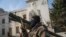 A Syrian opposition fighter holds a rocket launcher in front of the provincial government office, where an image of Syrian President Bashar Assad is riddled with bullets on the facade, in the aftermath of the opposition's takeover of Hama, Dec. 6, 2024.