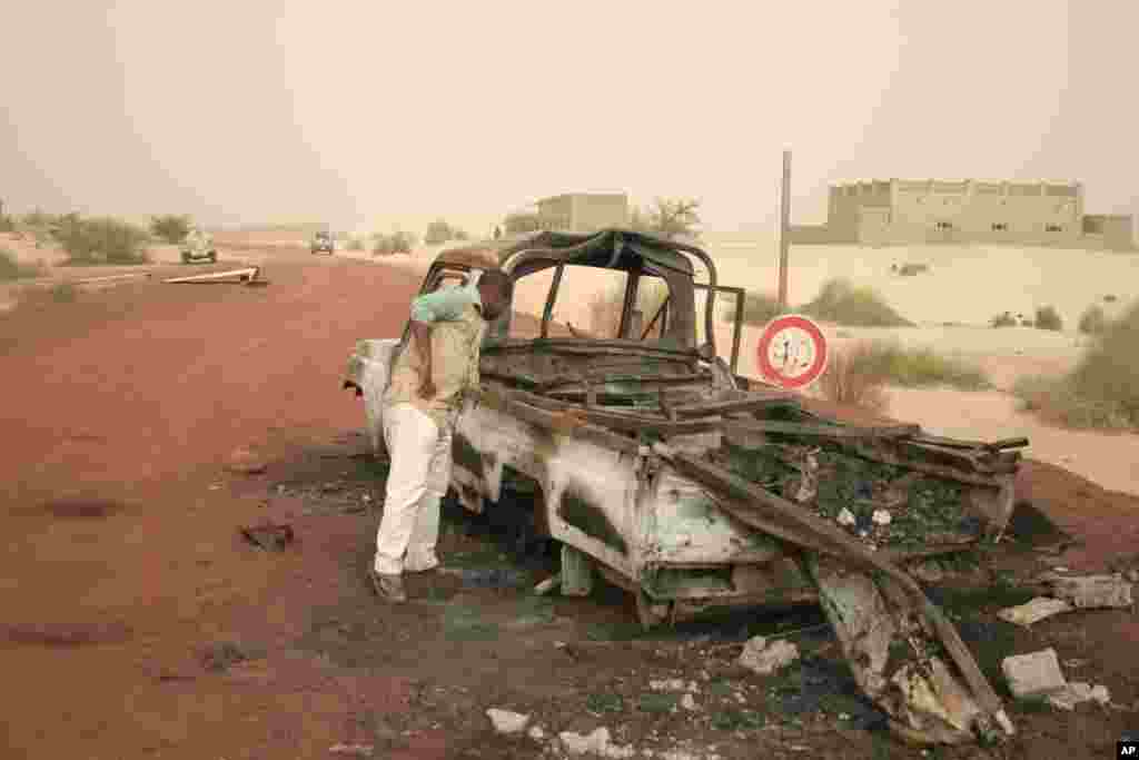 A man takes a close look at a burned-out truck in Timbuktu, Mali, January 31, 2013. 