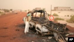 A man takes a close look at a burned-out truck in Timbuktu, Mali, January 31, 2013. 