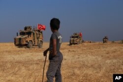 A Turkish armored vehicles patrol joins a joint ground patrol with American forces in the so-called "safe zone" on the Syrian side of the border with Turkey, Oct.4, 2019.