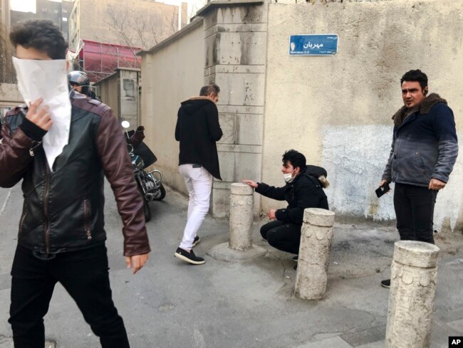 FILE - In this photo taken by an individual not employed by the Associated Press and obtained by the AP outside of Iran, people are affected by tear gas fired by anti-riot Iranian police to disperse demonstrators in a protest over Iran's weak economy, in
