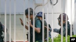 Japanski novinar Yuki Kitazumi podiže ruke dok ga prati policija po dolasku u policijsku stanicu Myaynigone u gradu Sanchaung u Yangonu u Mjanmaru, februar 2021.