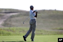 FILE - President Barack Obama follows through on a swing as he tees off while golfing at Vineyard Golf Club in Edgartown, Mass., Aug. 20, 2014. A day earlier, the U.S. government confirmed that Islamic State militants had beheaded journalist James Foley.