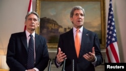 Britain's Foreign Secretary Phillip Hammond, left, and U.S. Secretary of State John Kerry deliver a statement at a press conference in London, Feb. 21, 2015. 
