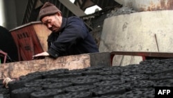 A worker stacks coal briquettes at a coal distribution business in Huaibei, central China's Anhui province, January 30, 2013. 