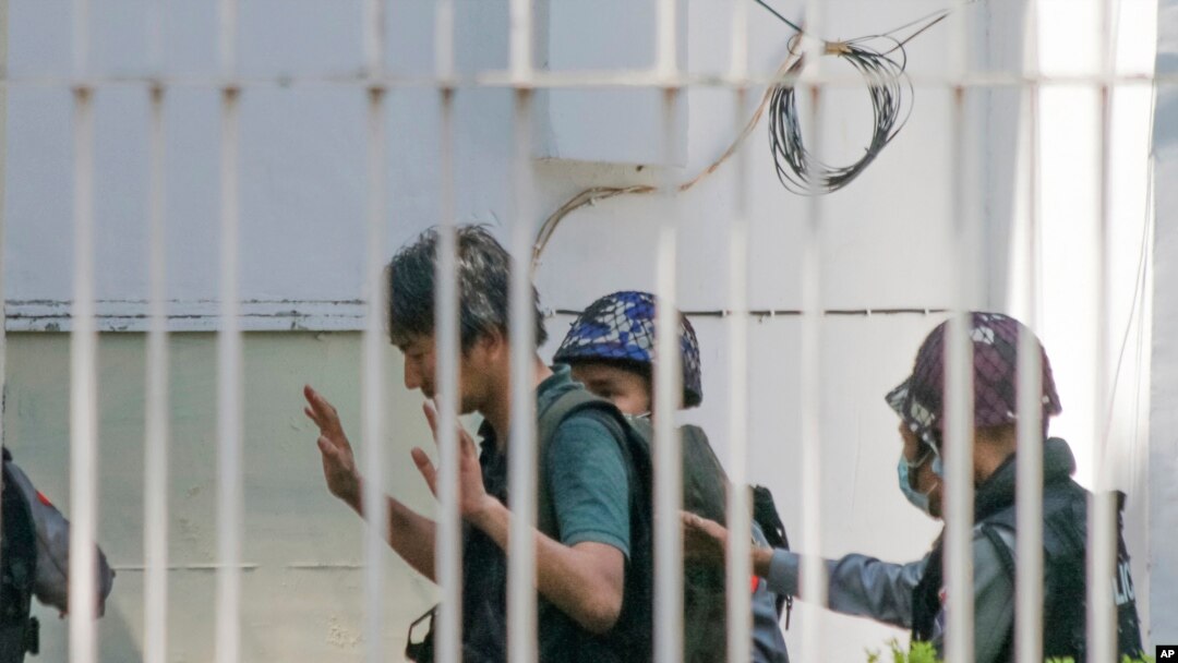 Jurnalis Jepang Yuki Kitazumi mengangkat tangannya saat dikawal oleh polisi setibanya di kantor polisi Myaynigone di Sanchaung,Yangon, Myanmar, 26 Februari 2021. Kitazumi kembali ke Jepang pada 14 Mei 2021 setelah dibebaskan. (AP)