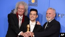 Personel band Queen, Brian May (kiri) dan Roger Taylor (kanan), mengapit Rami Malek, aktor terbaik dan peraih penghargaan film drama terbaik dalam film "Bohemian Rhapsody" pada ajang tahunan ke-76 Golden Globe Awards, di Beverly Hills, California, 6 Januari 2019.