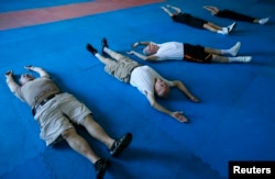 Parkinson's patients Jerry Held (L), Jim Coppula (2nd L) and Dan Cathcart (3rd L) stretch as they begin their workout at Rock Steady Boxing in Costa Mesa, California September 16, 2013.