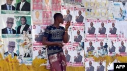Un homme se tient à côté des affiches de la campagne électorale à Freetown, le 9 mars 201.
