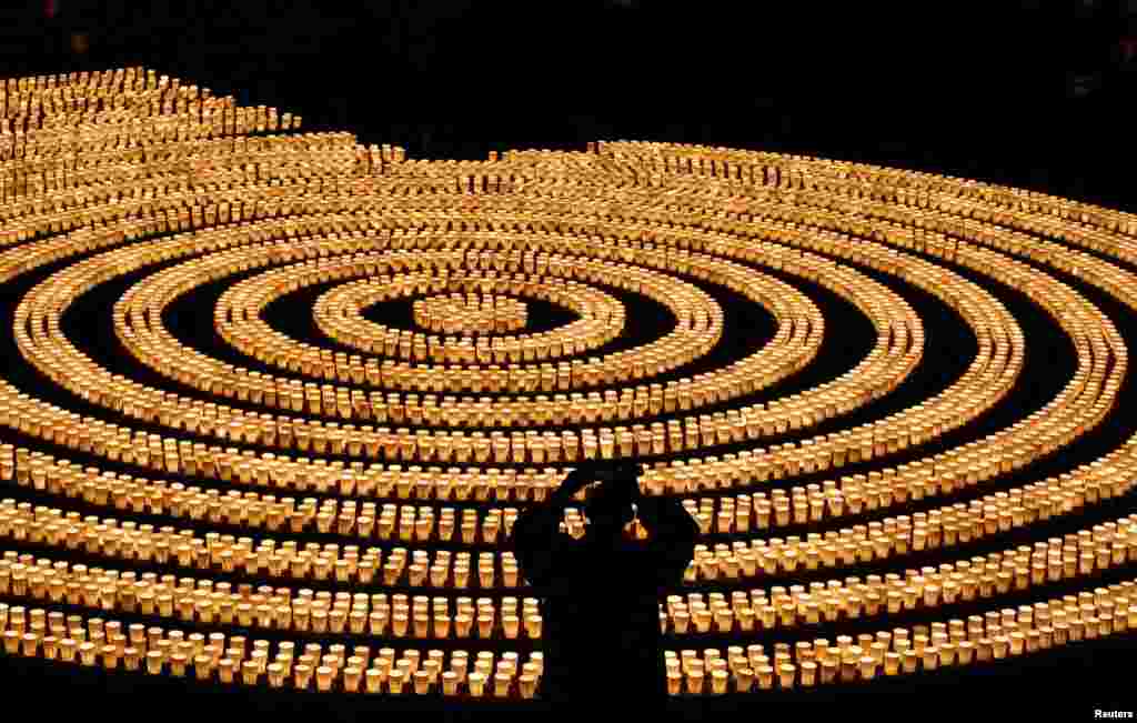 A staff wearing a protective mask, amid the COVID-19 outbreak, takes picture of 6,500 candle lights as he prepares for a ceremony to wish for overcoming the pandemic and good luck in the upcoming New Year at Hasedera Buddhist temple&nbsp;in Kamakura, south of Tokyo, Japan, Dec. 31, 2021.