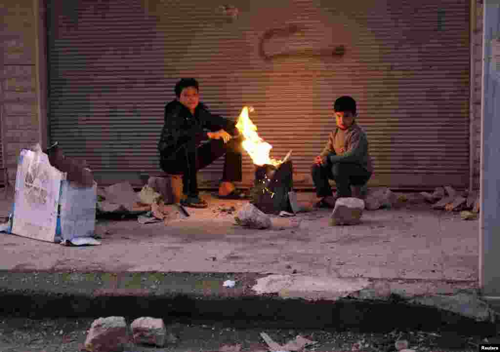 Boys warm up next to a fire outside a building in the Ain Tarma neighborhood of Damascus, Syria, February 5, 2013.