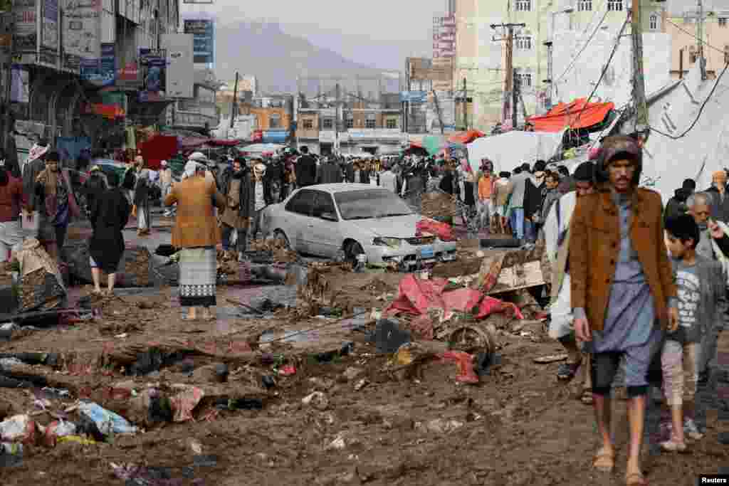 People walk on a damaged street in an area flooded by heavy rains in Sana'a, Yemen.