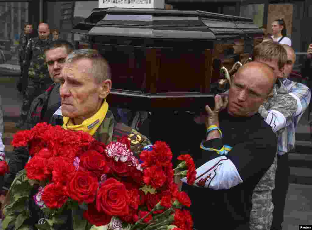 Mourners carry a coffin containing the body of Rodion Dobrodomov, a member of the Ukrainian National Guard killed during a battle in Mariupol on May 9, at his funeral, in Kyiv, May 12, 2014.