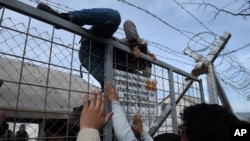 An Afghan refugee jumps the fence as he tries to enter Macedonia at the Greek-Macedonia borderline near the northern Greek village of Idomeni, Feb. 22, 2016. 