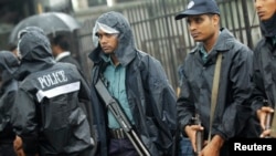 Police officers stand guard in front of the gate of International Crimes Tribunal (ICT) before a verdict against Bangladesh Jamaat-e-Islami chief Motiur Rahman Nizami in Dhaka, June 24, 2014. The ICT postponed the verdict due to his illness, local media r