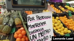 Un cartel advierte sobre mantener distancia social en un puesto de venta de frutas y verduras en Montevideo, Uruguay, el 27 de julio de 2020.