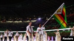 Tokyo 2020 Olympics - The Tokyo 2020 Olympics Opening Ceremony - Olympic Stadium, Tokyo, Japan - July 23, 2021. Flag bearers Peter Purcell-Gilpin of Zimbabwe and Donata Katai of Zimbabwe lead their contingent during the athletes' parade at the opening cer