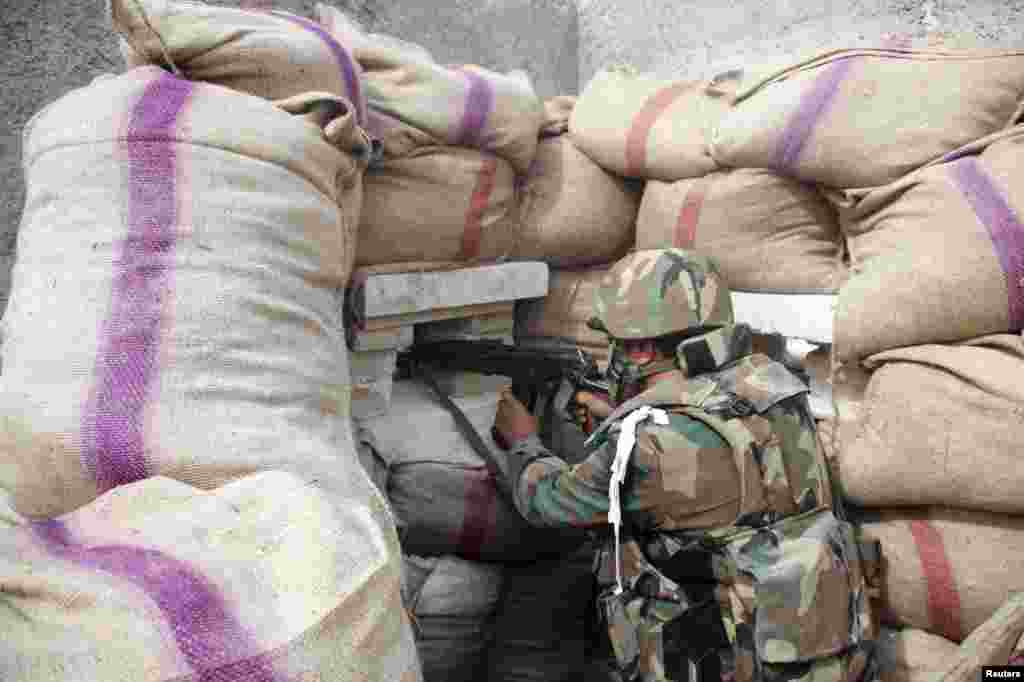 A Syrian Army soldier loyal to Syria&#39;s President Bashar al-Assad takes a position behind sandbags as he points his weapon in Ard al-Hamra, Aleppo, Feb. 27, 2014.&nbsp;