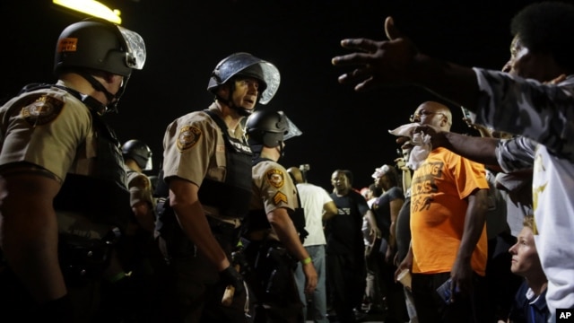 Policías y manifestantes se enfrentaron a lo largo de la avenida West Florissant, en Ferguson, Missouri, el lunes, 10 de agosto de 2015.