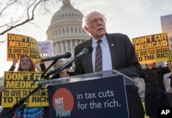 Sen. Bernie Sanders, I-Vt., joins protesters outside the Capitol as Republicans in the Senate work to pass their sweeping tax bill.