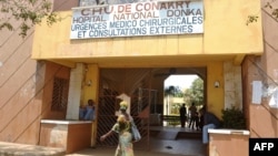 People walk in front of the Donka hospital in Conakry, Guinea, March 27, 2014. 