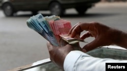 FILE - A money changer counts Pakistani rupee notes in Karachi.
