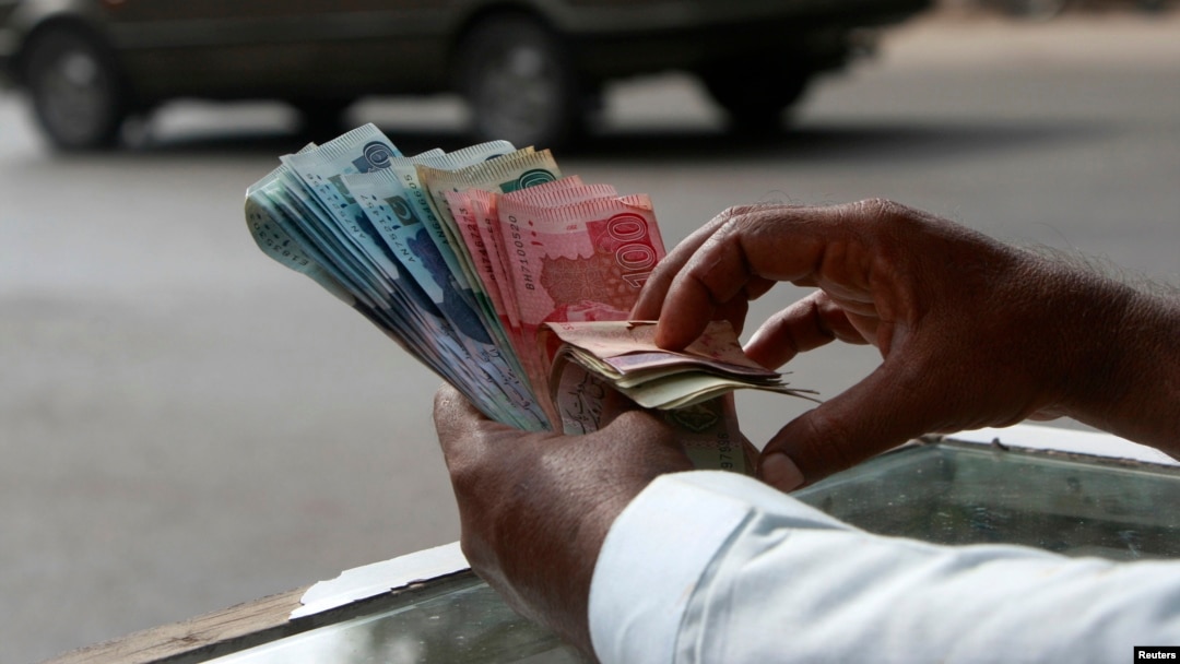 FILE - A money changer counts Pakistani rupee notes in Karachi.
